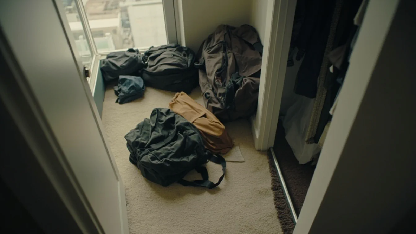 Three personal item bags collapsed flat in a small apartment closet: a Vancropak backpack, Narwey duffel, and WANDF duffel, with a carry-on suitcase beside them and a window showing city buildings.