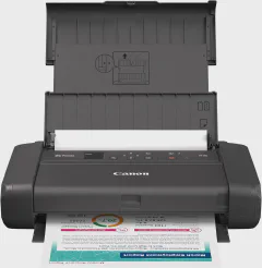 Canon PIXMA TR160 portable printer on a wooden home office desk beside a laptop, notebook, and coffee mug